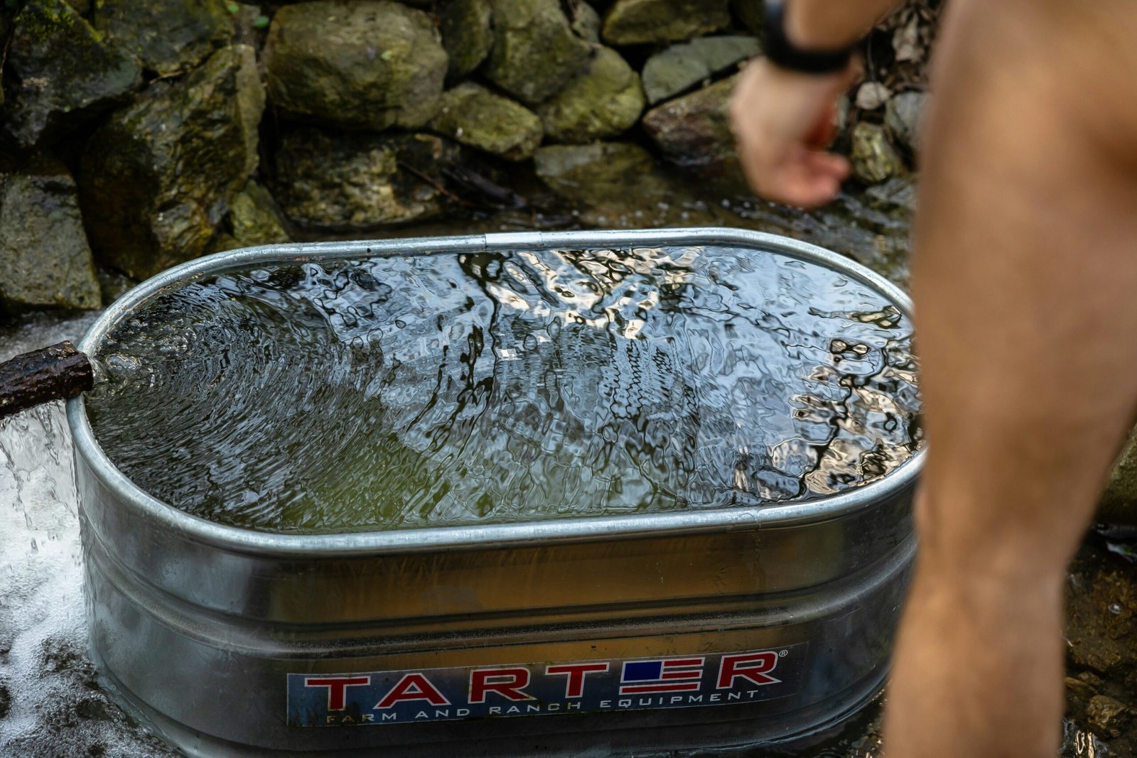 a man standing next to a metal tub filled with water