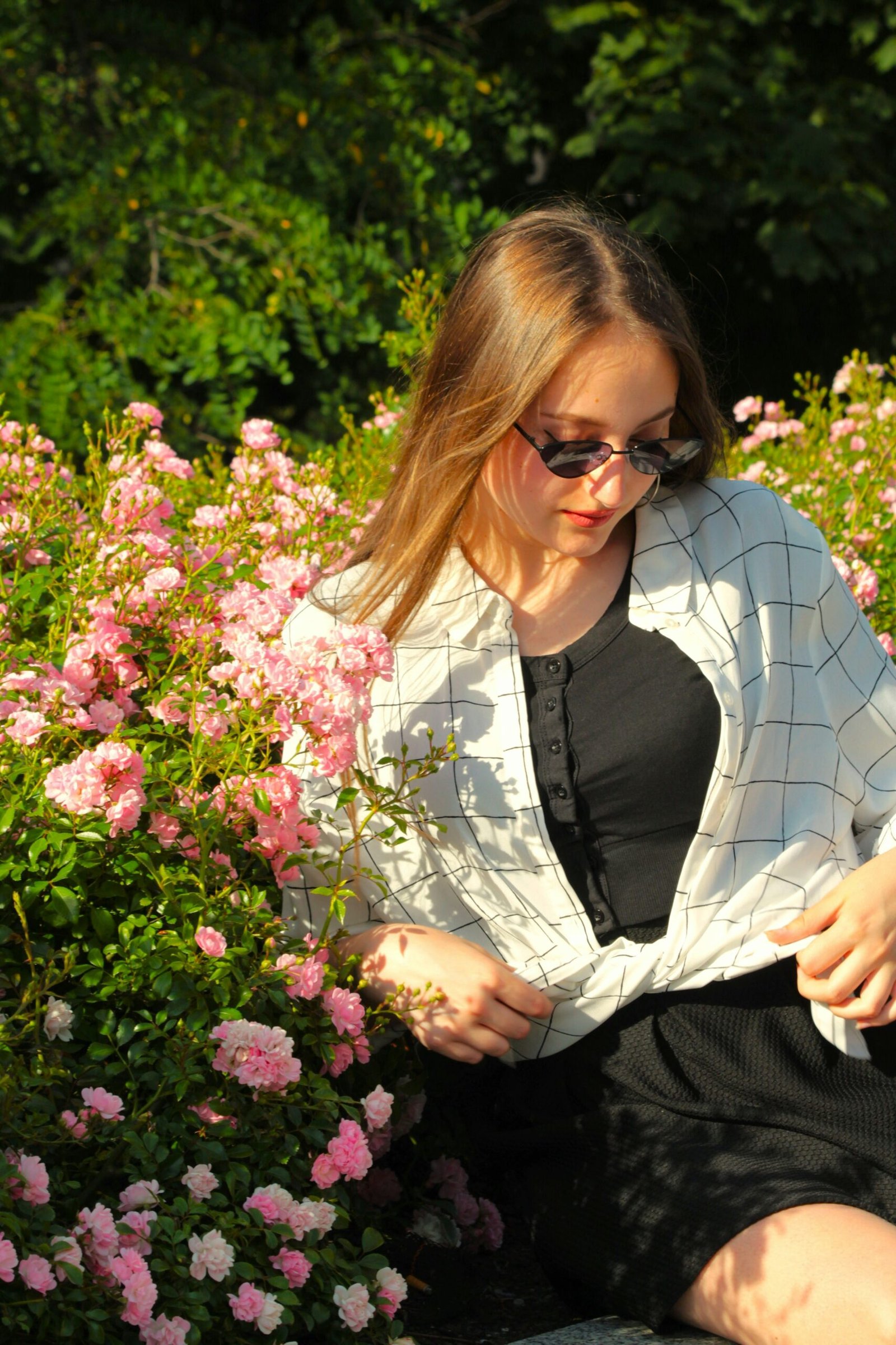 A woman sitting on a bench in front of flowers